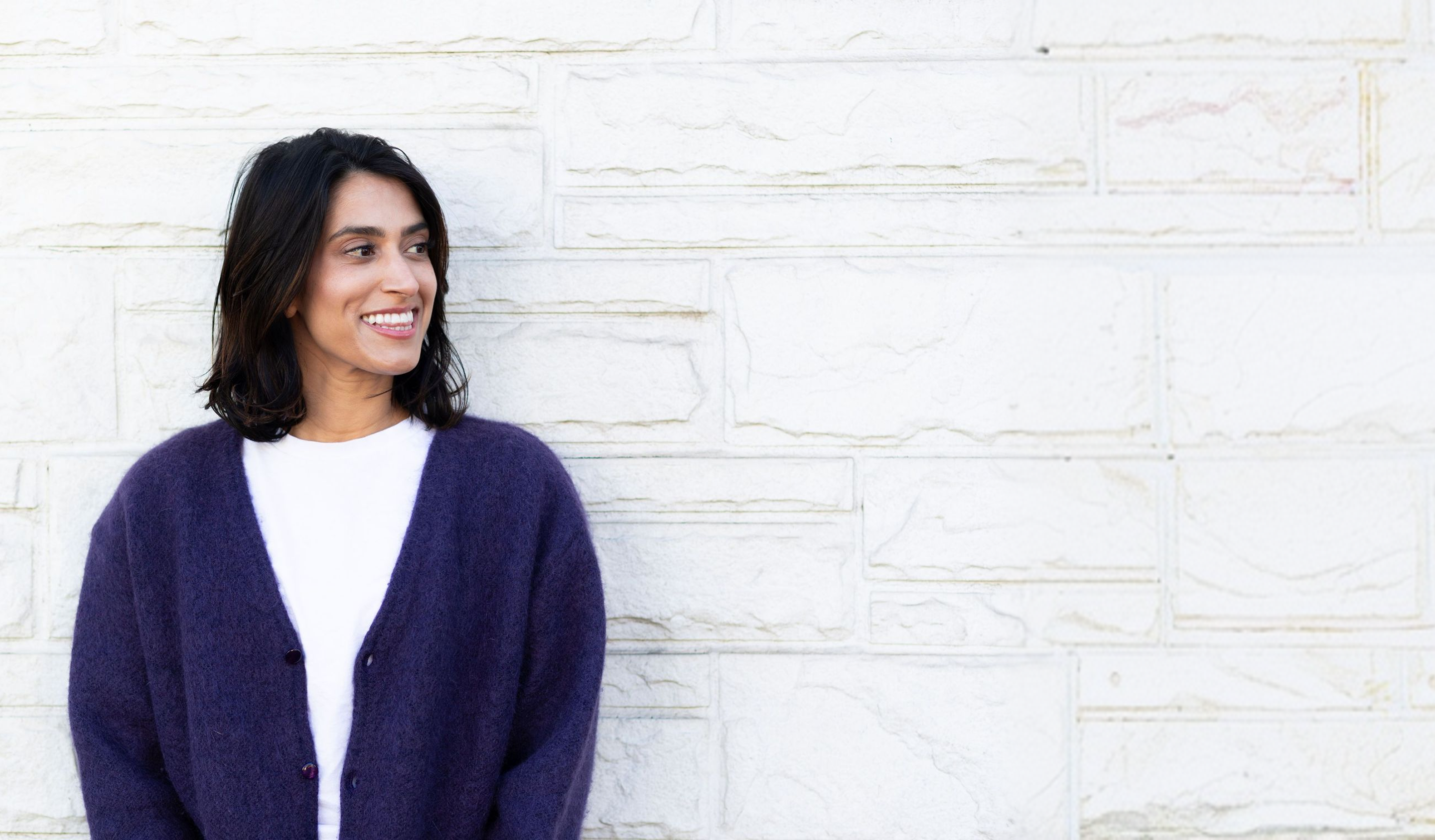 Darshini Patel laughing against a white brick wall